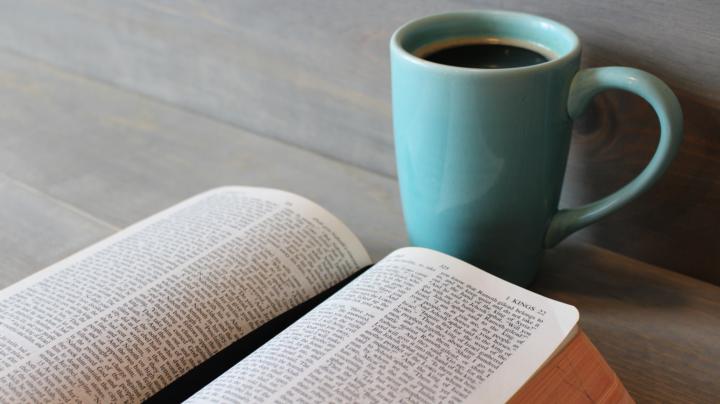 Bible with coffee mug on a table